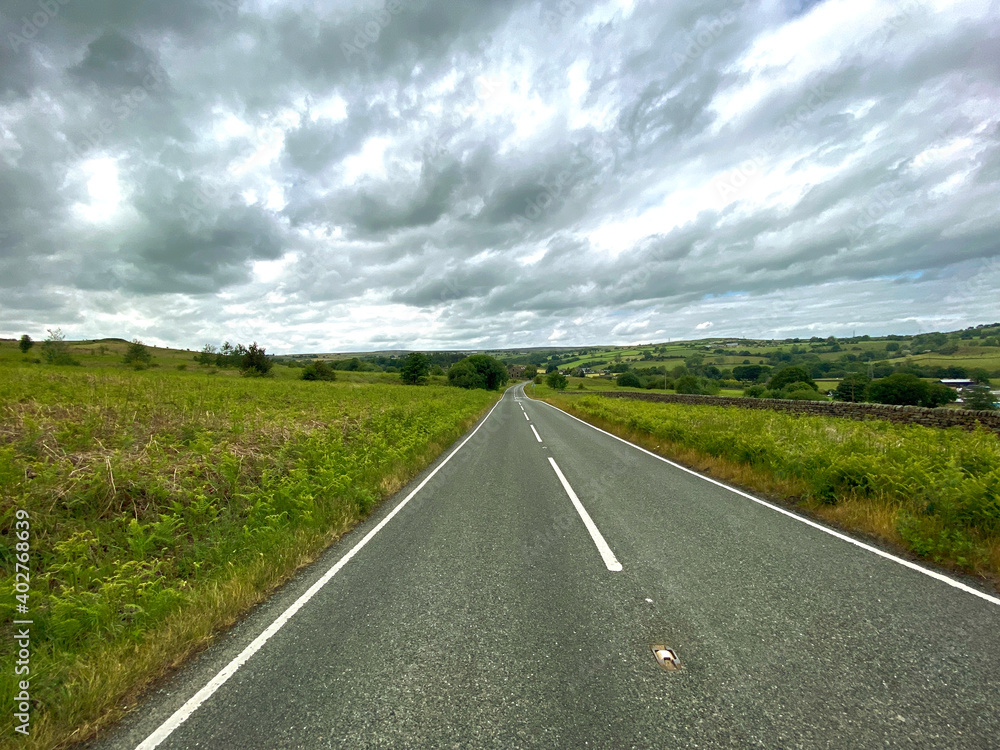 View along. Hawksworth Road, with heavy rain clouds above in, Shipley, Bradford, UK