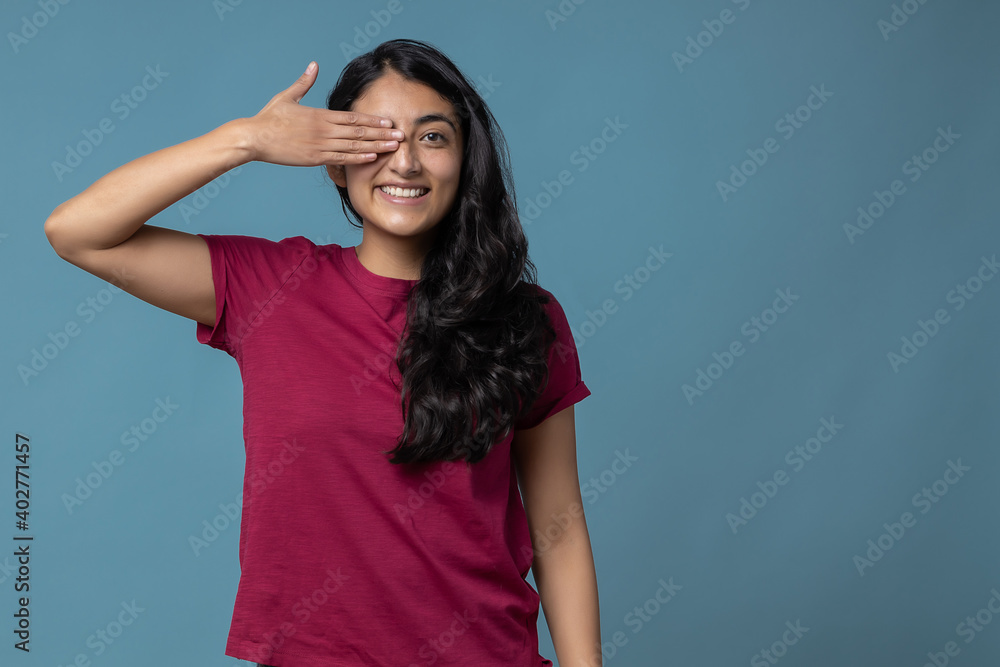 Mexican millennial woman covering one eye with her hand and smiling Mexican millennial woman covering one eye with her hand and smiling