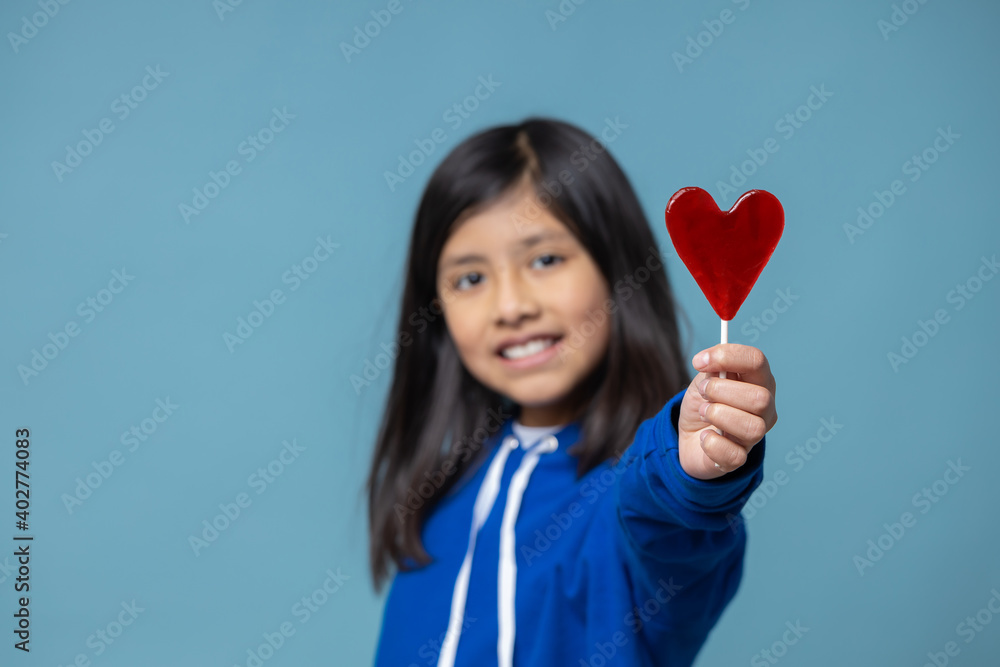 Mexican latin girl holding heart shaped lollipop self love concept Mexican latin girl holding heart shaped lollipop self love concept