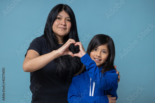 mexican mother and daughter doing a heart with their hands isolated, girl power