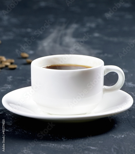 A white cup of coffee on a black background. Morning coffee. Coffee cup