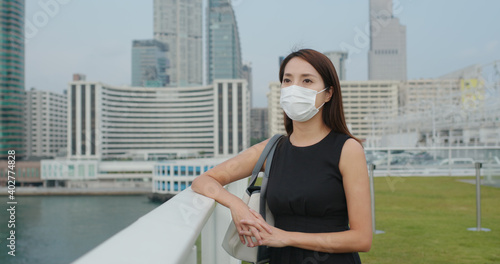 Woman wear face mask and look at the city view © leungchopan