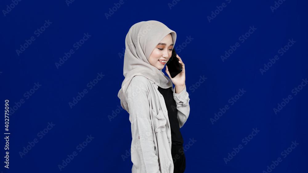 Asian hijab woman calling on the phone isolated blue background Asian hijab woman calling on the phone isolated blue background