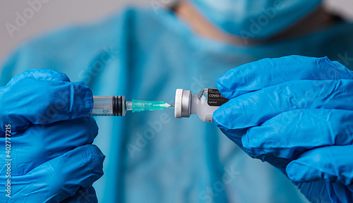 Close-up of a doctor's hands inserting the syringe into the Covid-19 vaccine vial