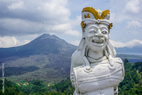 Balinese statue with a drum on the background of the Batur volcano