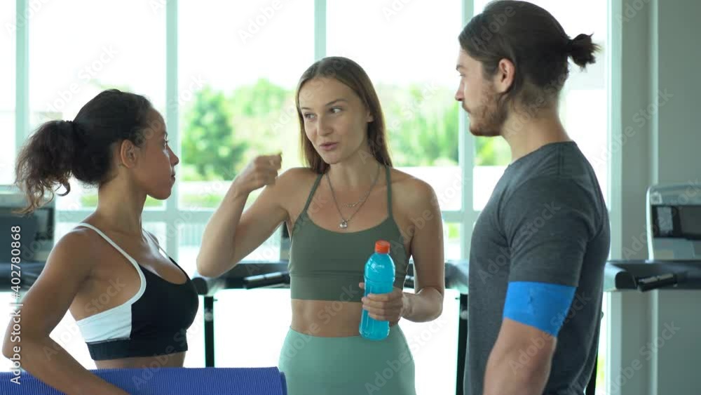 group of fitness woman and sport man holding yoga mat conversation after exercising yoga class in the gym. Group of young fit people standing talking and relaxing in sport club after workout training group of fitness woman and sport man holding yoga mat conversation after exercising yoga class in the gym. Group of young fit people standing talking and relaxing in sport club after workout training
