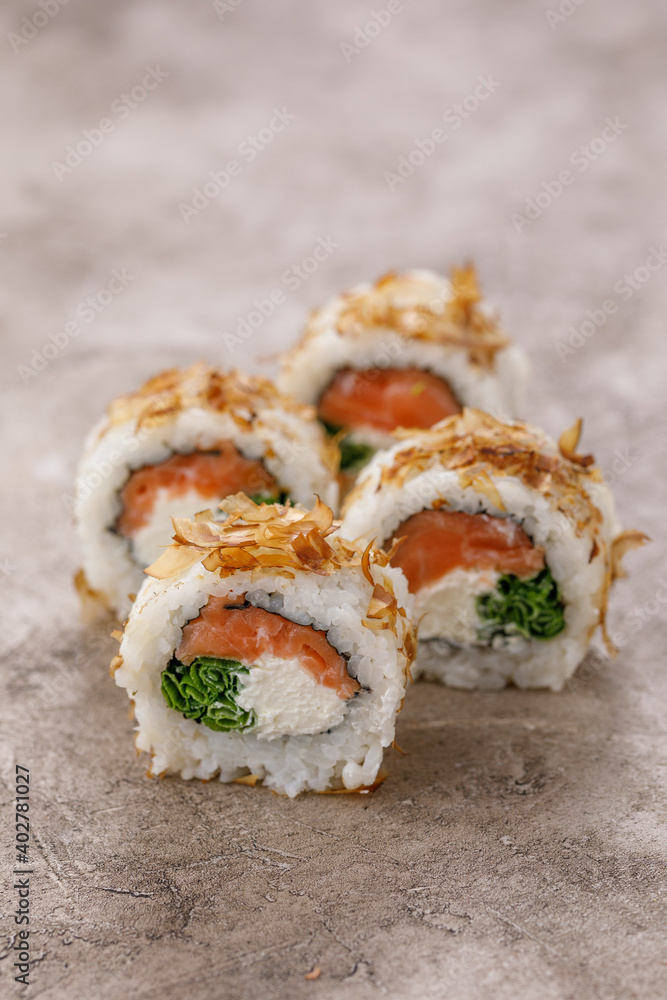Sushi rolls with tuna shavings on a textured still life background. Restaurant concept. Close-up. Sushi rolls with tuna shavings on a textured still life background. Restaurant concept. Close-up.
