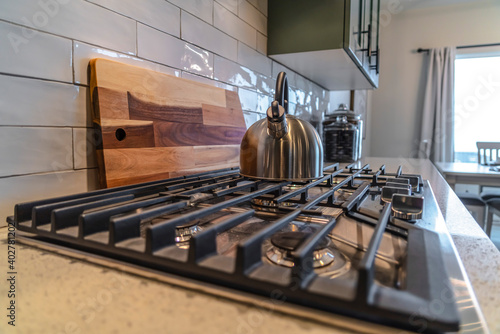 Cooktop with kettle over burner and cast iron grate inside a residential kitchen photo