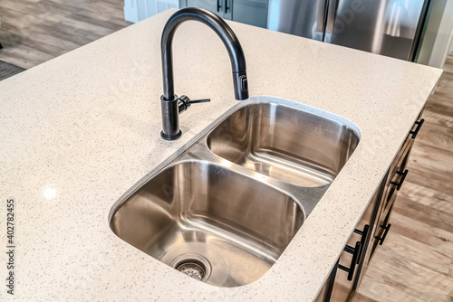 Foto Black curved faucet over stainless steel undermount sink with double basins