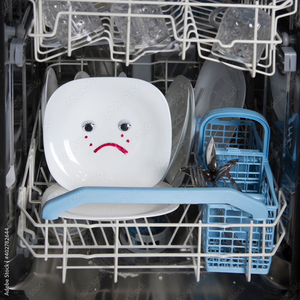 Poorly washed dishes in dishwasher. Integrated dishwasher with white