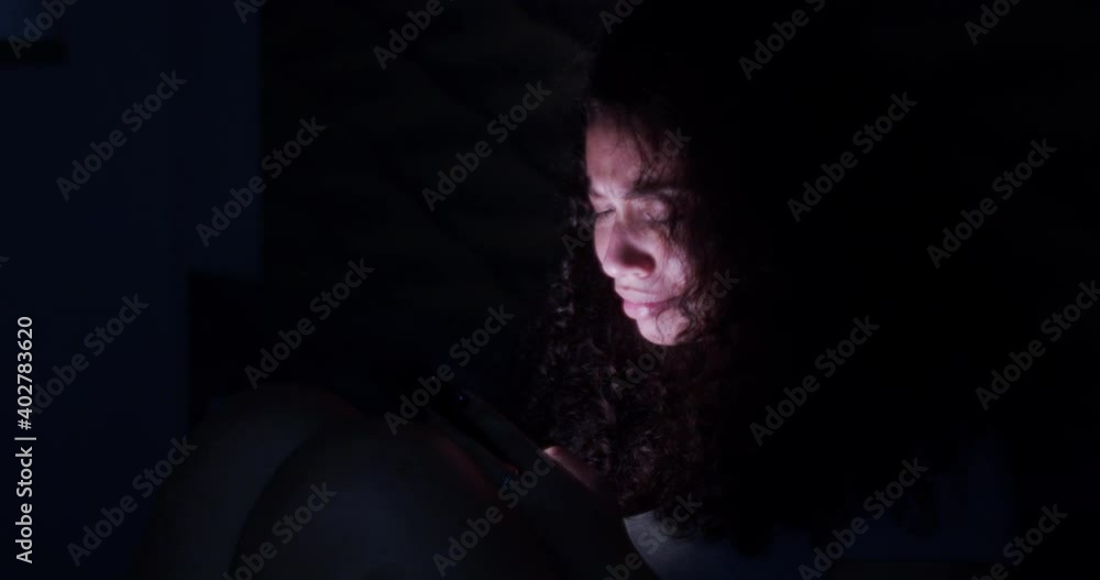 Dramatic lifestyle of young sad and depressed Latin American woman crying in bed holding mobile phone victim of cyber bullying or broken heart in her bedroom. 4K.
