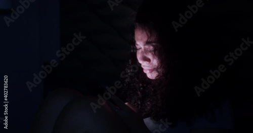 Dramatic lifestyle of young sad and depressed Latin American woman crying in bed holding mobile phone victim of cyber bullying or broken heart in her bedroom. 4K.