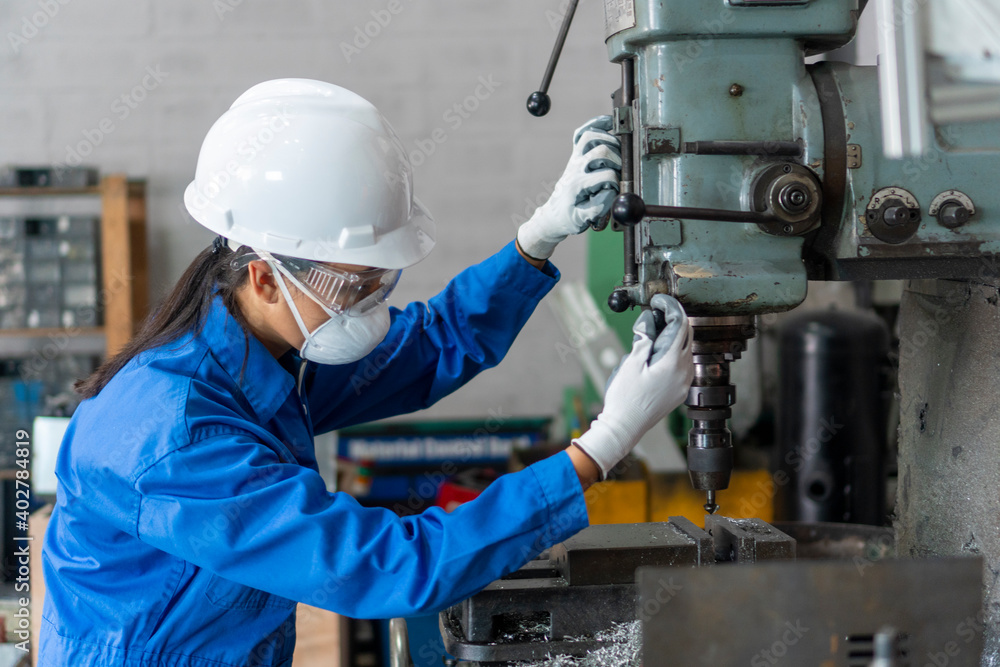 Asian woman who is an industrial engineer working on machines and working at an industrial machine with a digital tablet. heavy work Concept of industrial workers Asian woman who is an industrial engineer working on machines and working at an industrial machine with a digital tablet. heavy work Concept of industrial workers