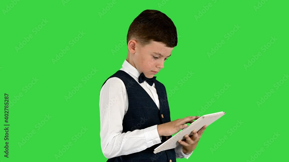 Concentrated boy using digital tablet while standing on a Green Screen, Chroma Key. Concentrated boy using digital tablet while standing on a Green Screen, Chroma Key.