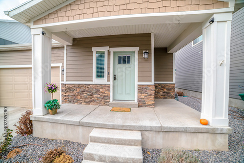 Front door and sidelight against brick wall and wood siding of home with porch