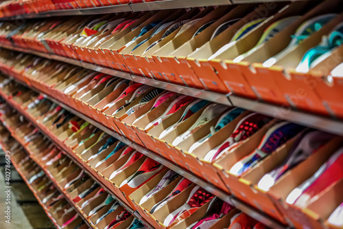 a lot of sports sneakers in the orange paper boxes on shelf ready to sales.