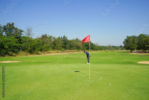 Red flag at the beautiful golf course at the sunrise time. Beautiful golf course in a sunny day. Background evening golf course has sunlight shining down. Golf course in the countryside