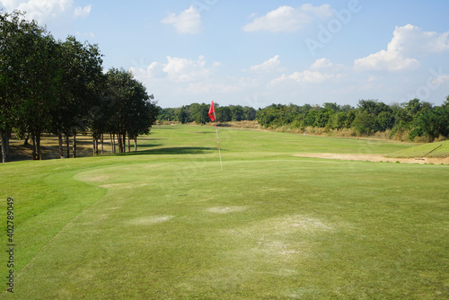 Red flag at the beautiful golf course at the sunrise time. Beautiful golf course in a sunny day. Background evening golf course has sunlight shining down. Golf course in the countryside