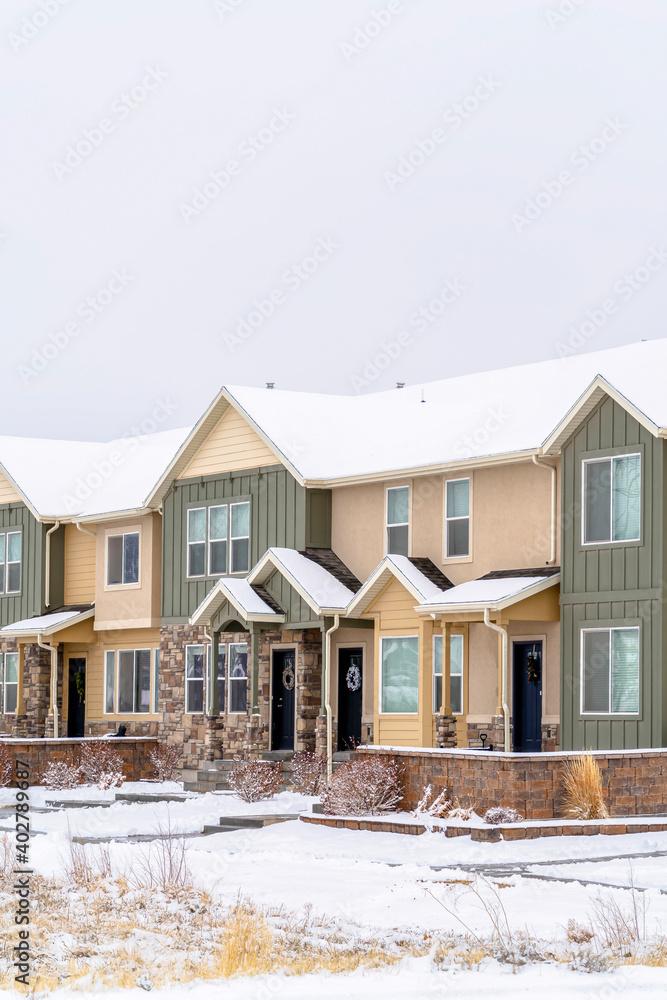 Two storey apartment facade with snowy yard and roof against white sky in winter Two storey apartment facade with snowy yard and roof against white sky in winter