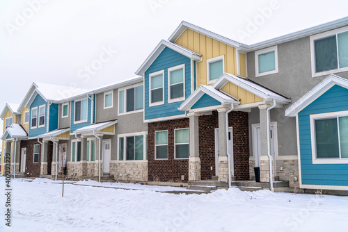 Two storey houses with colorful walls in a neighborhood landscape with snow
