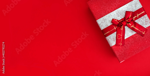 red gift box with a bow on a red background. copy space