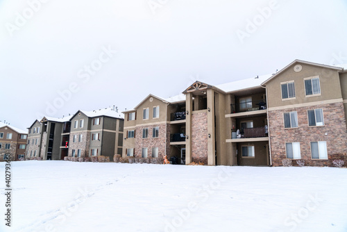 Facade of three storey brick apartment building with balconies and snowy roofs