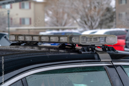 Light bar mounted on the roof of a black police car with droplets of rain water
