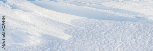 Beautiful winter background with snowy ground. Natural snow texture. Wind sculpted patterns on snow surface. Wide panoramic texture for background and design. © Andrei Stepanov