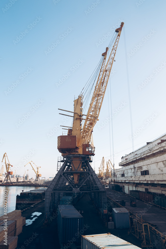 Fototapeta premium Yellow loading crane. Black Sea commercial port, container loading by crane. Shipping. Container import and export logistics, cargo harbor view. Panorama of harbor cranes.