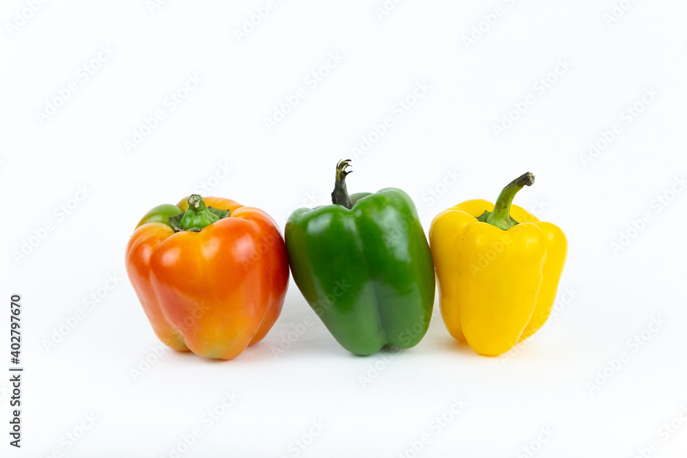 Fresh vegetables, juicy red, yellow, green peppers with a green stem stands on an isolated white background. Fresh vegetables. Fresh vegetables, juicy red, yellow, green peppers with a green stem stands on an isolated white background. Fresh vegetables.