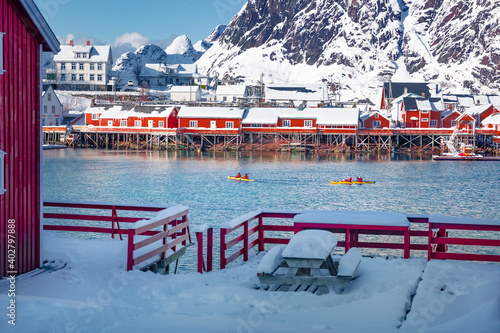 Tourists travel by kayak on the Norwegian Sea. Sunny morning scene of Hamnoy village, Lofoten Islands. Picturesque winter landscape over polar circle. Traveling concept background..