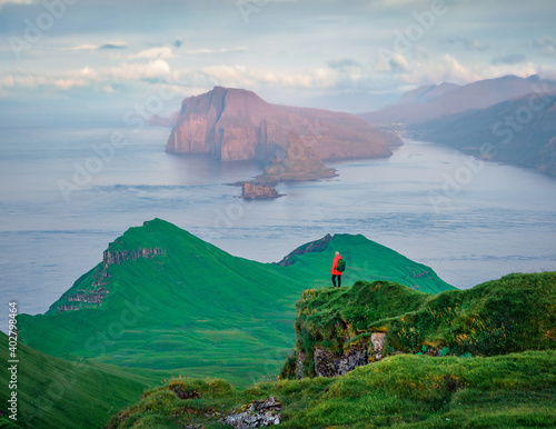 Tourist admiring of sunset on Alaberg cliffs, Faroe Islands, Denmark. Cold morning view of Mykines island with Vagar island on background. Atlantic seascape. photo