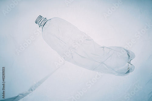 Plastic pollution. Zero waste. Ocean conservation. Ecology problem. Used creased empty bottle floating underwater on light blue copy space background.