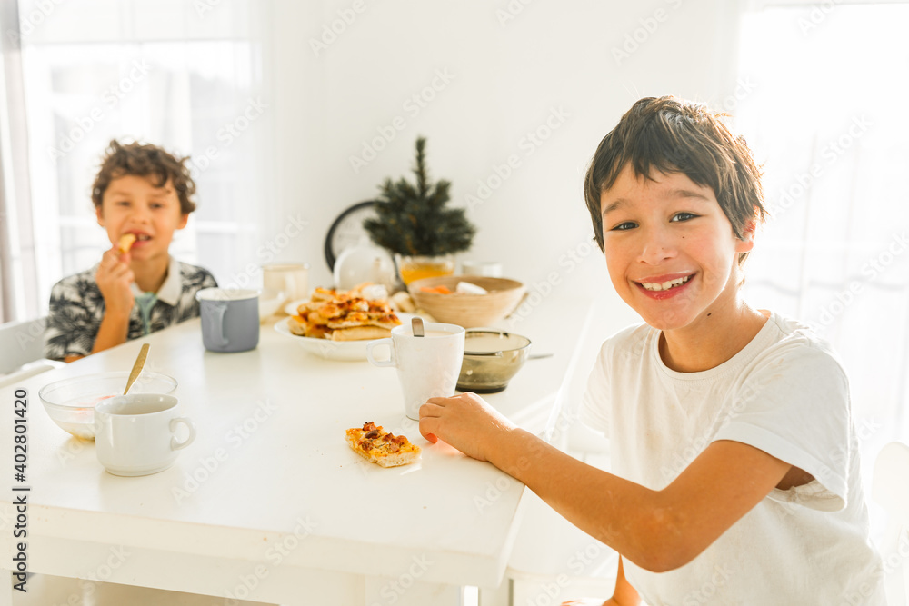 Portrait of smiling boys having breakfast at home two real siblings Portrait of smiling boys having breakfast at home two real siblings