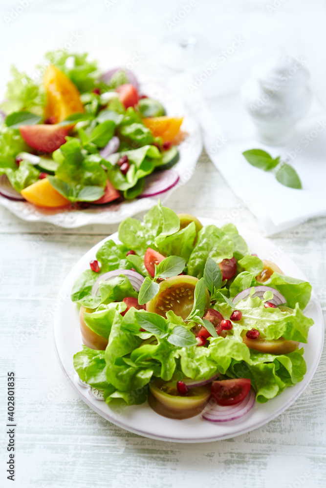 Salad with red and yellow Tomatoes and Pomegranate Seeds on bright wooden Background. Healthy Snack Idea. Salad with red and yellow Tomatoes and Pomegranate Seeds on bright wooden Background. Healthy Snack Idea.