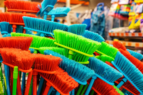 Plastic broom in different colors. Large assortment of brushes for cleaning premises in the DIY store. Trade in floor cleaning equipment
