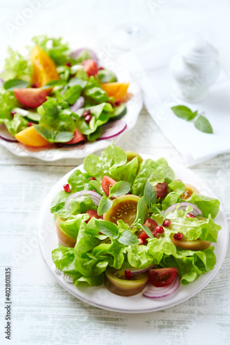 Salad with red and yellow Tomatoes and Pomegranate Seeds on bright wooden Background. Healthy Snack Idea.	