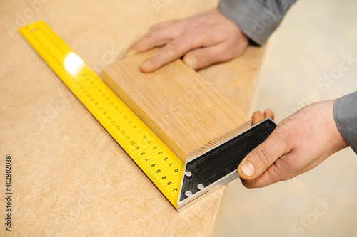 Carpentry works. The process of measuring a board with a ruler to measure angles. Close-up. View from above