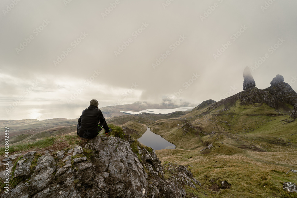 Un ragazzo ammira il paesaggio dello storr seduto su di una roccia