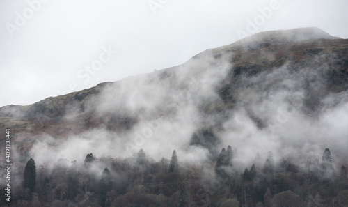 Epic dramatic landscape image of view from Elterwater across towards Langdale Pikes mountain range on foggy Winter morning © veneratio