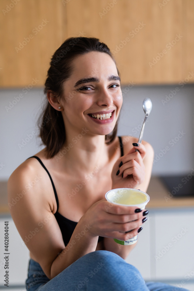 Portrait of young woman eating yogurt at home. Portrait of young woman eating yogurt at home.