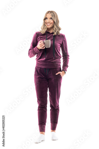 Happy confident young pretty woman in home comfy clothes with coffee or tea mug smile and looks up. Full body length isolated on white background.