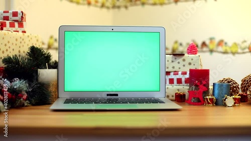 Green chroma-key laptop screen with New Year presents on background. Winter holidays. Connect with friends. Chroma-key notebook. Free content. Mock up monitor. Online greeting. Internet surfing