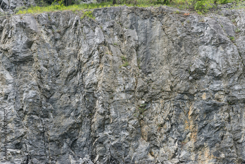 Quadro su tela Weathered rock face texture in old stone pit with parts of green