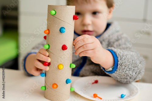 match a color. insert correct color pin to assigned hole. Concentrated baby face, working on new task.Toddler hands on paper tube. fine motoric skills, Montessori, ergotherapy, DIY