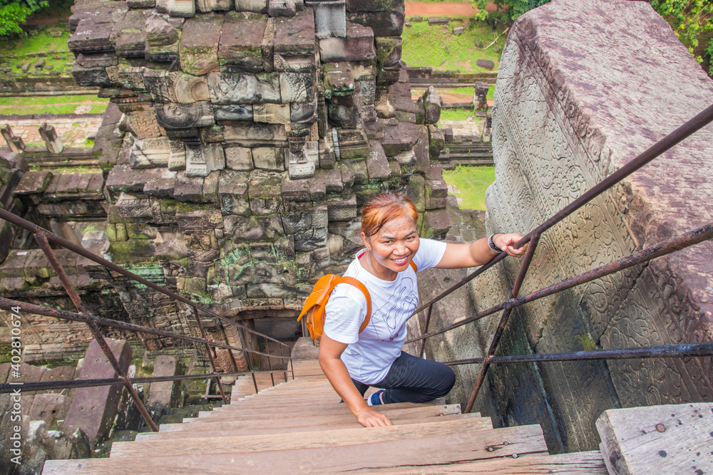 Fototapeta premium Angkor Wat Siem Reap Cambodia Southeast Asia Tour Thai Lady climbing in the temple ruin of Angkor Wat