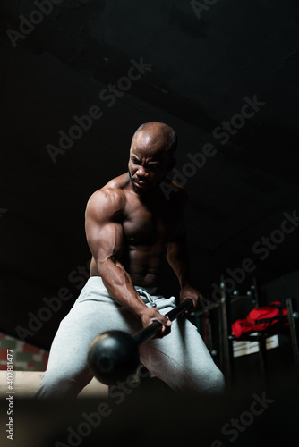 A man in sweatpants performs an exercise in the gym for training and striking. Power training © DmitryStock