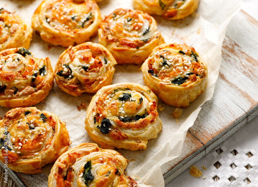 Fototapeta premium French Puff Pastry Pinwheels stuffed with salmon, cheese and spinach on on baking paper, close up view 