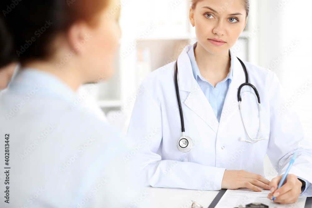 Doctor and patient are communicating while sitting at the table Doctor and patient are communicating while sitting at the table