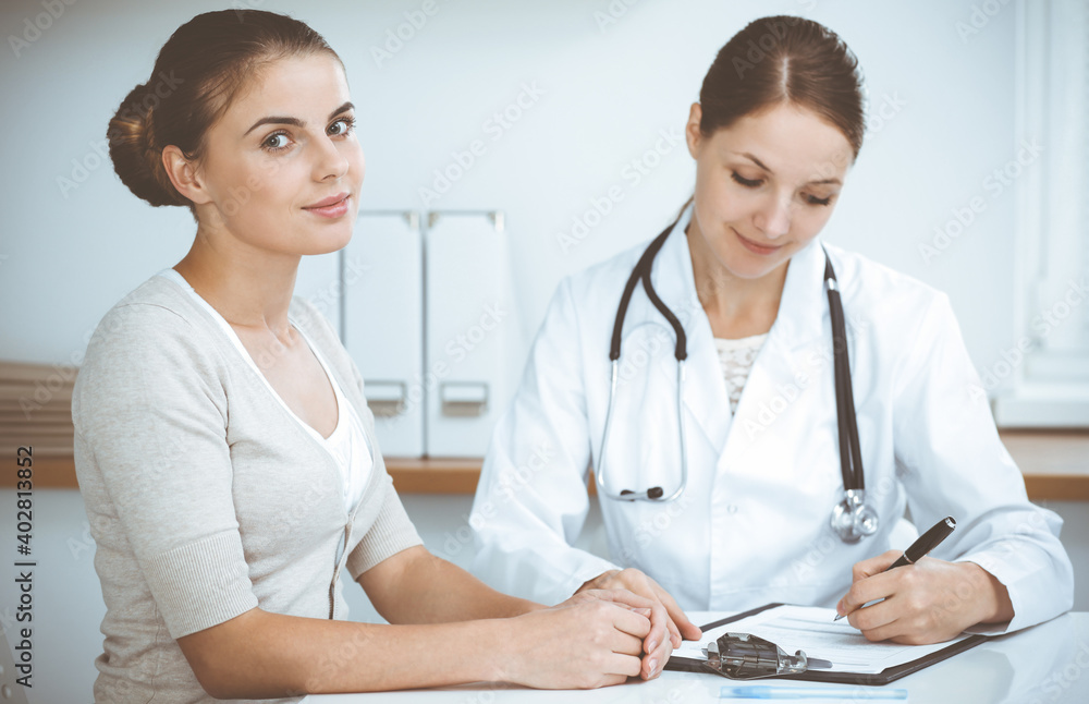 Doctor and patient are sitting and discussing health examination results in clinic office. Health care, medicine and good news concepts Doctor and patient are sitting and discussing health examination results in clinic office. Health care, medicine and good news concepts